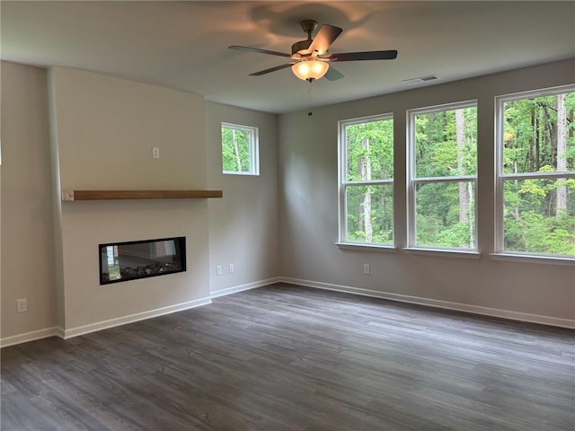 unfurnished living room with a glass covered fireplace, baseboards, ceiling fan, and dark wood-style flooring
