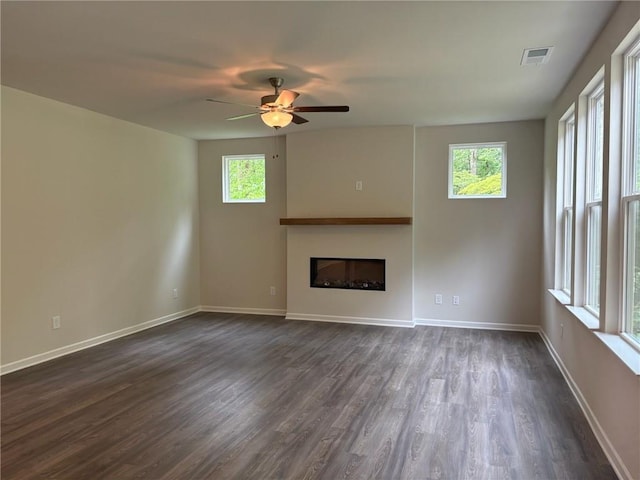 unfurnished living room featuring dark wood-style flooring, ceiling fan, a fireplace, baseboards, and visible vents