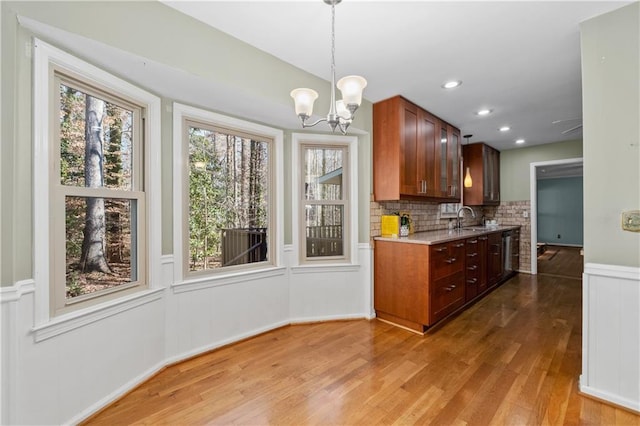 kitchen featuring hardwood / wood-style flooring, a chandelier, hanging light fixtures, decorative backsplash, and sink