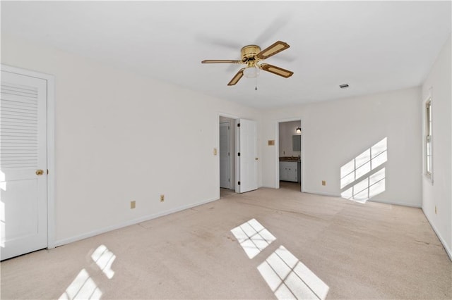 unfurnished bedroom featuring ceiling fan, light colored carpet, and connected bathroom