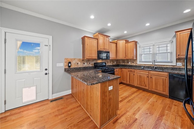 kitchen featuring sink, black appliances, kitchen peninsula, dark stone counters, and light wood-type flooring