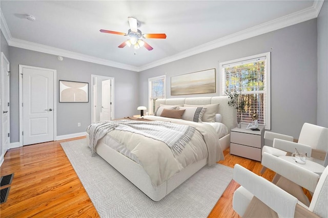 bedroom featuring ornamental molding, ceiling fan, light hardwood / wood-style floors, and ensuite bath