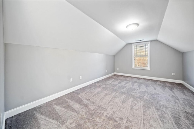 additional living space featuring vaulted ceiling and carpet flooring