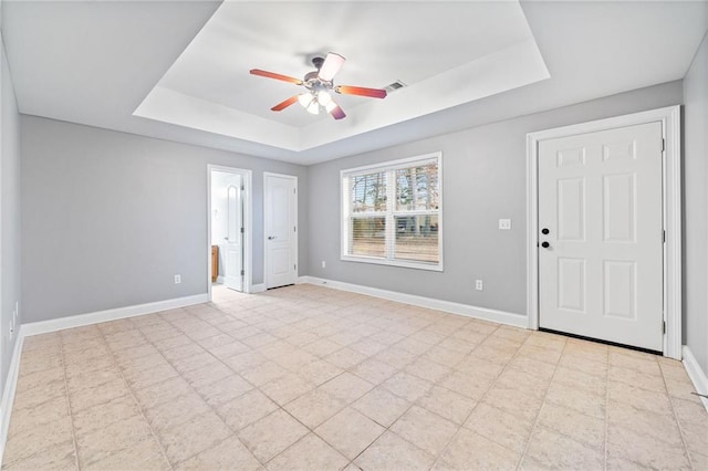 unfurnished room with ceiling fan and a raised ceiling