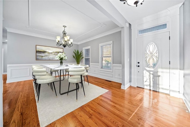 dining space with an inviting chandelier, crown molding, and light hardwood / wood-style floors