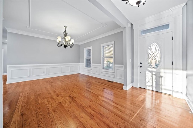 foyer entrance with an inviting chandelier, crown molding, and light wood-type flooring