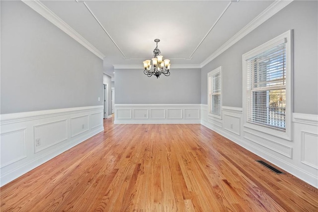 unfurnished dining area featuring crown molding, a chandelier, and light hardwood / wood-style floors