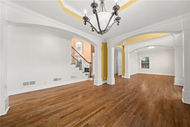 unfurnished living room featuring ornate columns, crown molding, hardwood / wood-style flooring, and a notable chandelier