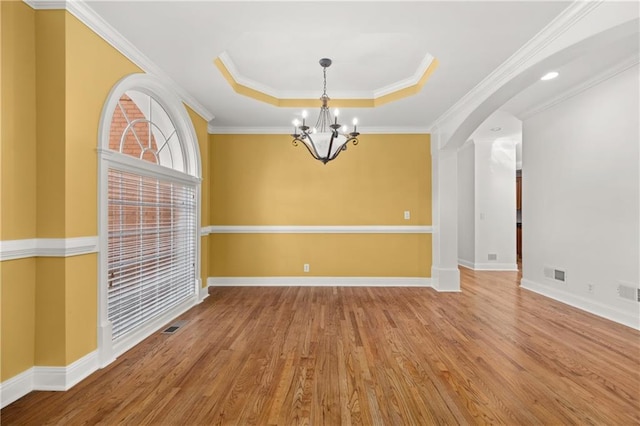 unfurnished room featuring a chandelier, hardwood / wood-style floors, a raised ceiling, and crown molding