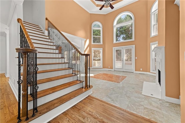 entrance foyer featuring french doors, ornamental molding, ceiling fan, light hardwood / wood-style flooring, and a high ceiling