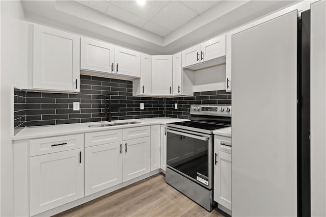 kitchen featuring a paneled ceiling, stainless steel range with electric stovetop, sink, light hardwood / wood-style flooring, and white cabinets