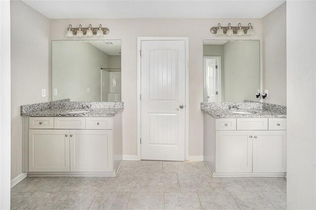 bathroom with baseboards, a sink, and two vanities
