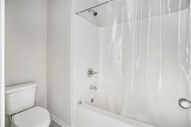bathroom featuring baseboards, toilet, and shower / tub combo