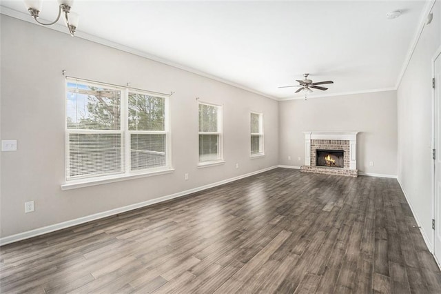 unfurnished living room with a fireplace, baseboards, ceiling fan, ornamental molding, and dark wood-style flooring