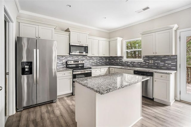 kitchen with ornamental molding, stainless steel appliances, a sink, visible vents, and light wood-style flooring