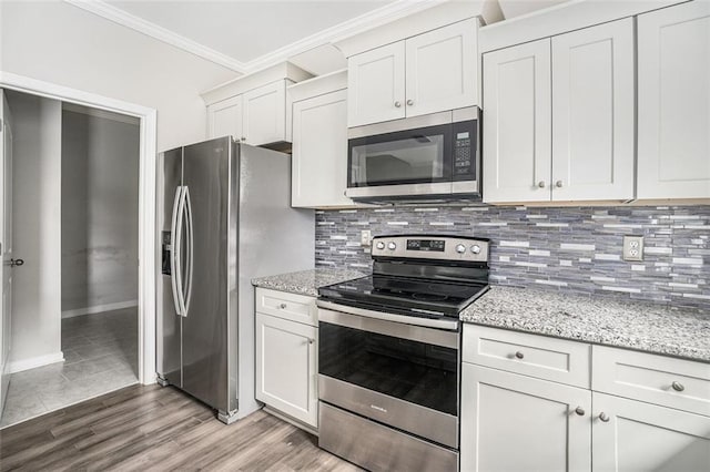 kitchen with ornamental molding, backsplash, light wood-style floors, light stone countertops, and appliances with stainless steel finishes