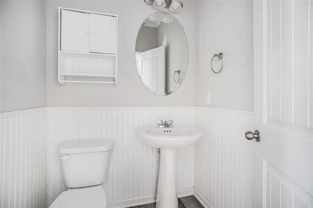 bathroom featuring a sink, toilet, and wainscoting