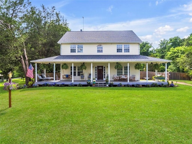 country-style home featuring ceiling fan, a front yard, covered porch, and a patio area