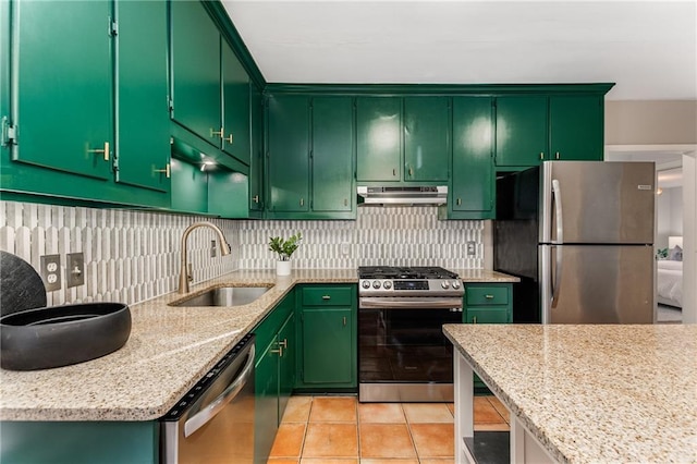 kitchen featuring light tile patterned floors, tasteful backsplash, stainless steel appliances, under cabinet range hood, and a sink