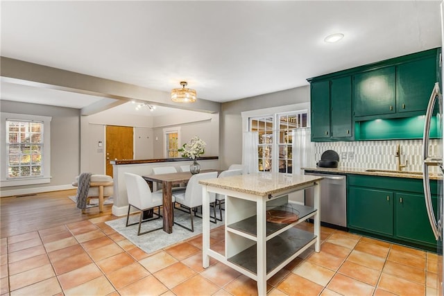 kitchen featuring dishwasher, light tile patterned floors, backsplash, and green cabinetry