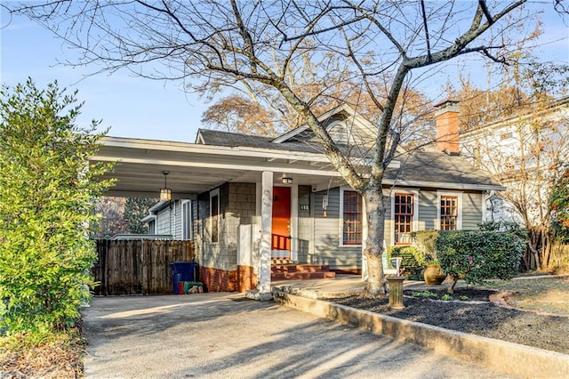 view of front of home featuring a carport, a chimney, fence, and driveway