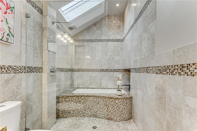 full bathroom featuring tiled bath, toilet, lofted ceiling with skylight, a tile shower, and tile walls