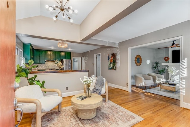 interior space with baseboards, vaulted ceiling, ceiling fan with notable chandelier, and light wood-style floors