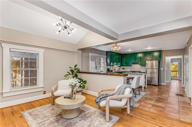 living area featuring vaulted ceiling with beams, visible vents, a chandelier, and baseboards