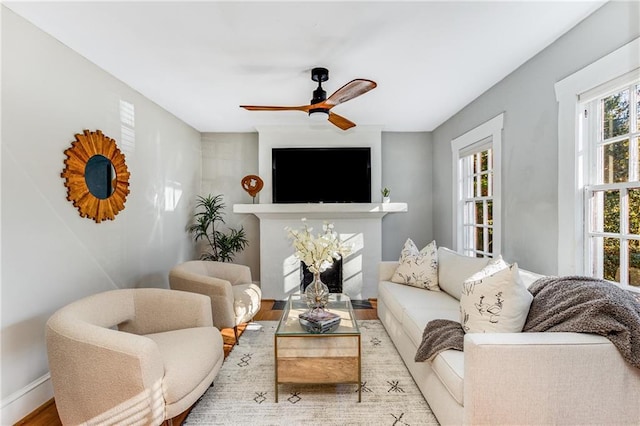 living area featuring a ceiling fan, baseboards, and wood finished floors