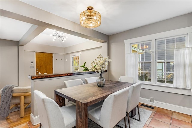 dining room with baseboards, a healthy amount of sunlight, visible vents, and an inviting chandelier