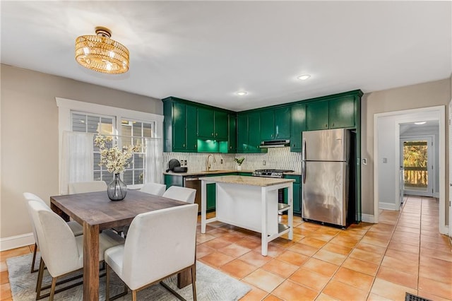 kitchen with a sink, appliances with stainless steel finishes, backsplash, and green cabinetry