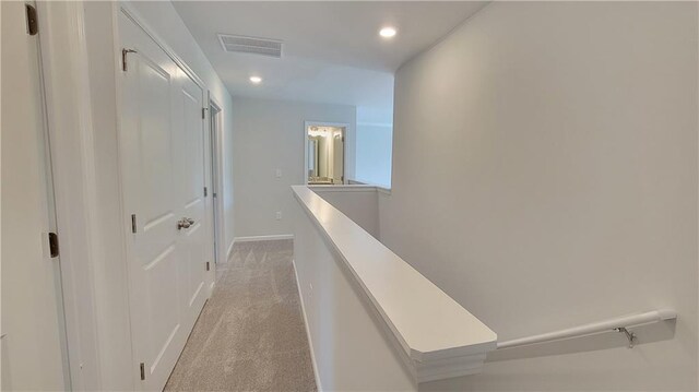 hall featuring visible vents, baseboards, an upstairs landing, light carpet, and recessed lighting