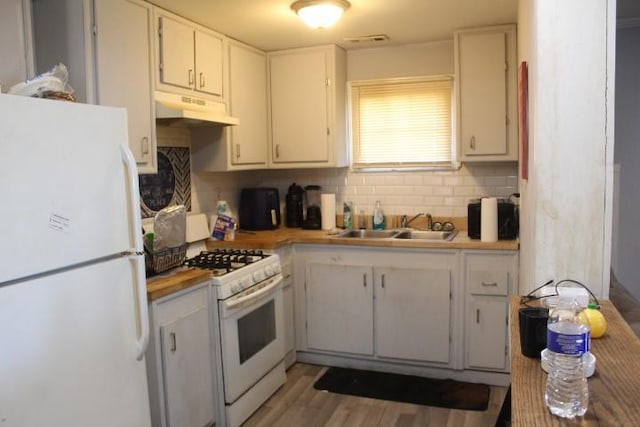 kitchen featuring sink, white cabinetry, light wood-type flooring, white appliances, and backsplash