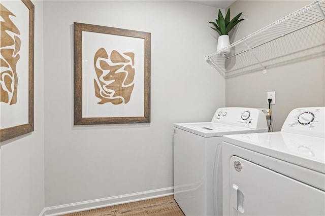 clothes washing area featuring baseboards, separate washer and dryer, and laundry area