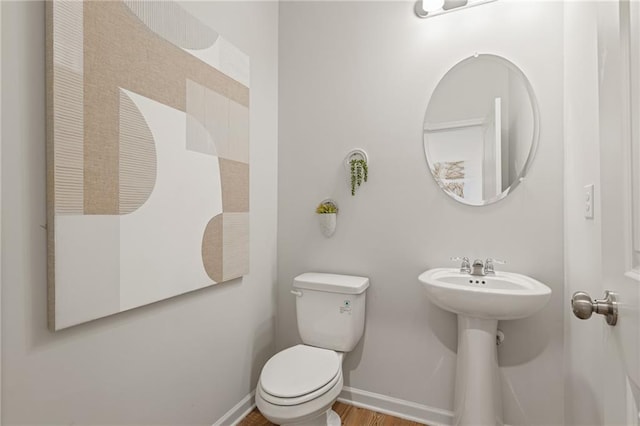 bathroom with baseboards, toilet, and wood finished floors