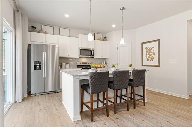 kitchen featuring white cabinetry, light wood-type flooring, backsplash, and stainless steel appliances