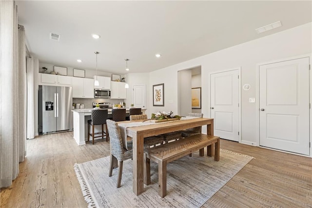 dining space with light wood-style flooring, recessed lighting, and visible vents