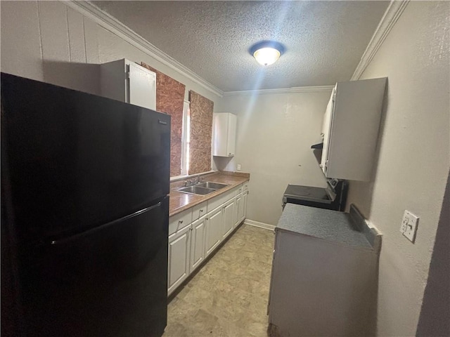 kitchen with ornamental molding, electric stove, a sink, a textured ceiling, and freestanding refrigerator