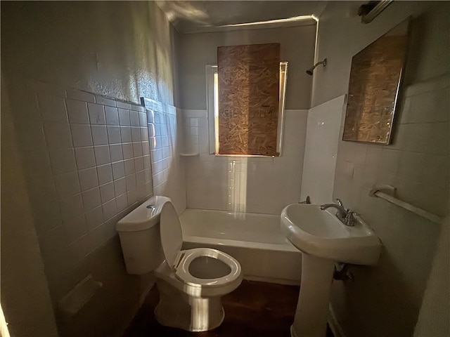 bathroom with a sink, toilet, tile walls, and bathtub / shower combination