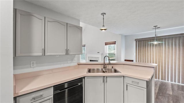 kitchen with light countertops, dishwasher, a peninsula, and a sink