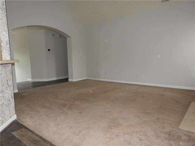 carpeted empty room featuring vaulted ceiling