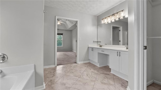 bathroom with a washtub, double vanity, a sink, a textured ceiling, and baseboards