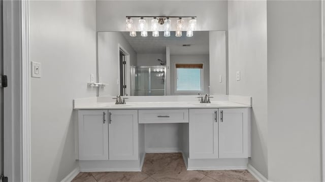 full bathroom with double vanity, a shower stall, baseboards, and a sink