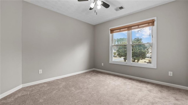 carpeted spare room with a ceiling fan, visible vents, and baseboards