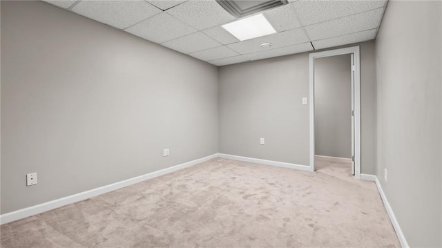 empty room with carpet, a drop ceiling, and baseboards