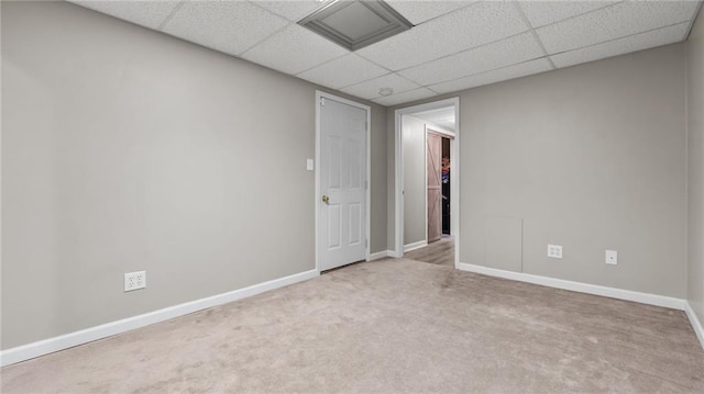 spare room with a paneled ceiling, carpet, and baseboards