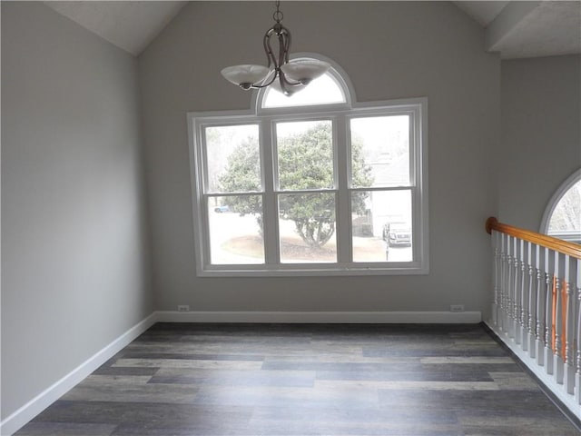 spare room with lofted ceiling, dark hardwood / wood-style floors, and a chandelier