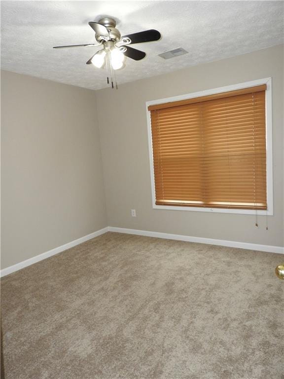 carpeted spare room featuring ceiling fan and a textured ceiling