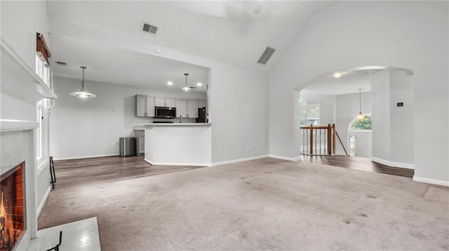 unfurnished living room with carpet floors, a fireplace, visible vents, and arched walkways