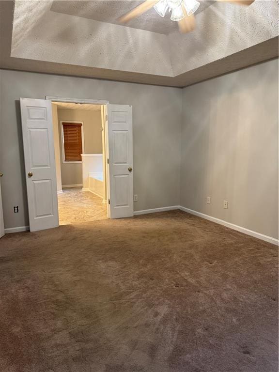 unfurnished room featuring a textured ceiling, a raised ceiling, ceiling fan, and carpet flooring